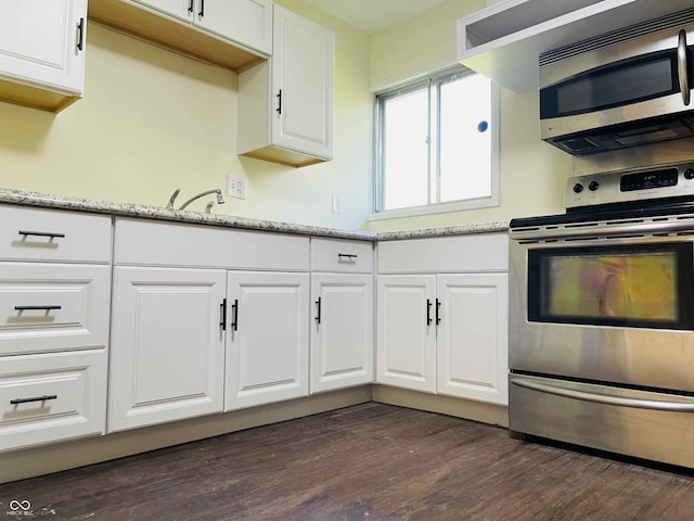 kitchen with dark wood-type flooring, sink, white cabinetry, light stone counters, and stainless steel appliances