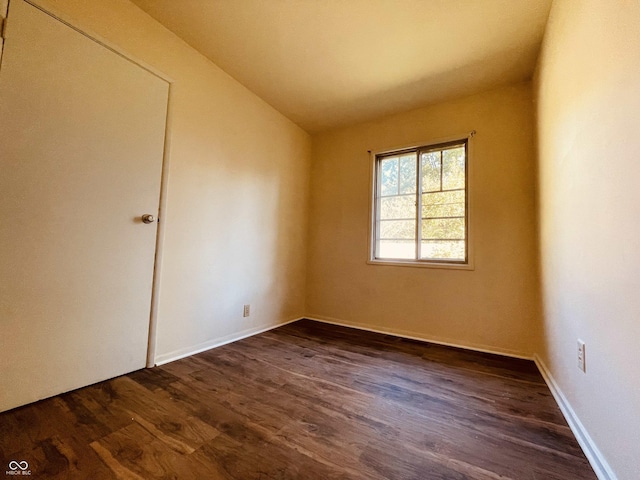 empty room with lofted ceiling and dark wood-type flooring