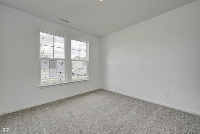 spare room with carpet floors, visible vents, and baseboards