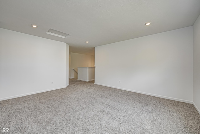 carpeted empty room with recessed lighting, attic access, and baseboards