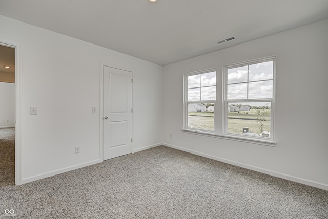 carpeted spare room featuring visible vents and baseboards