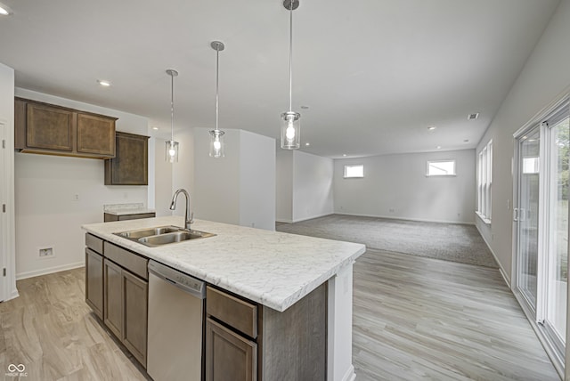 kitchen with a sink, light countertops, stainless steel dishwasher, an island with sink, and decorative light fixtures