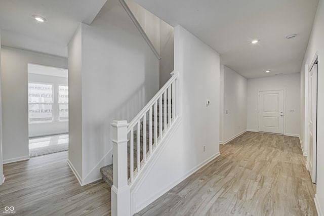 corridor featuring light wood-type flooring, baseboards, and recessed lighting