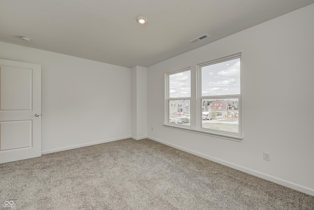 spare room featuring baseboards, visible vents, and light colored carpet