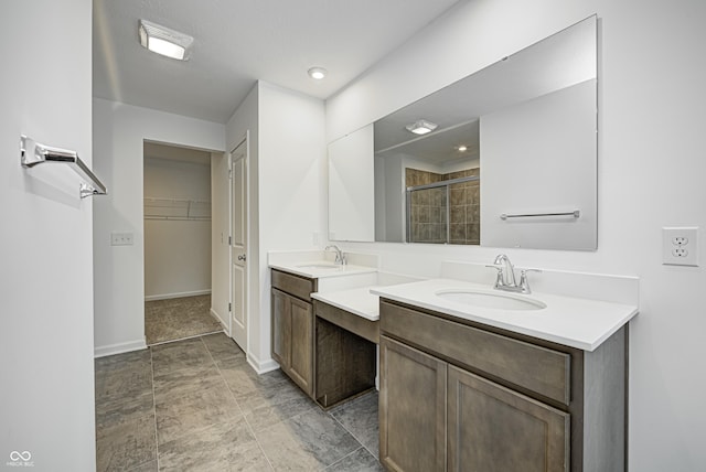 bathroom featuring double vanity, a shower stall, a walk in closet, and a sink