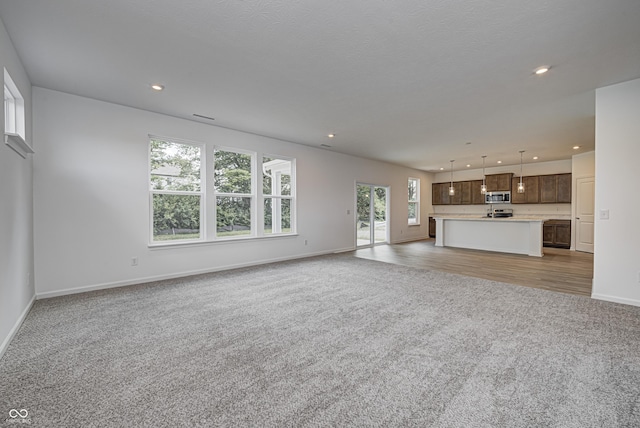 unfurnished living room featuring recessed lighting, carpet flooring, and baseboards