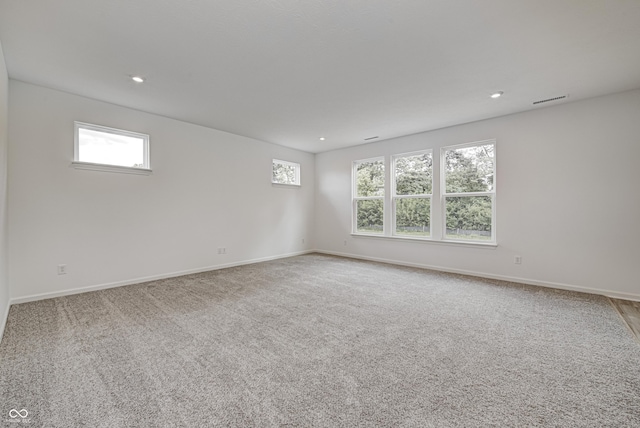 carpeted empty room with baseboards, visible vents, and recessed lighting