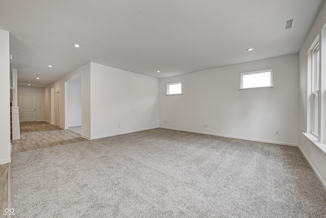 unfurnished room featuring recessed lighting, a healthy amount of sunlight, visible vents, and light carpet