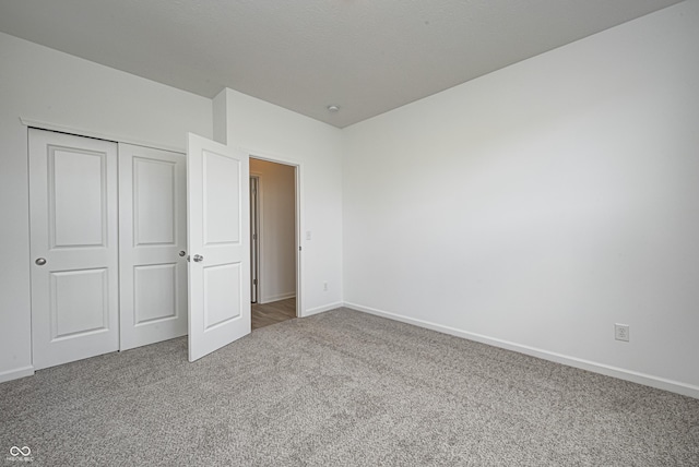 unfurnished bedroom with carpet floors, a closet, and baseboards