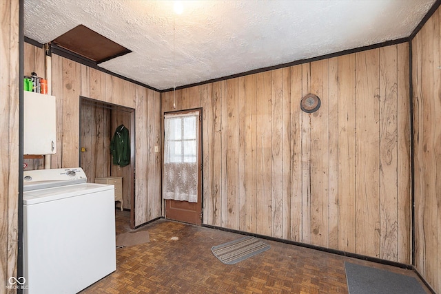 clothes washing area featuring dark parquet flooring, wooden walls, washer / dryer, and a textured ceiling