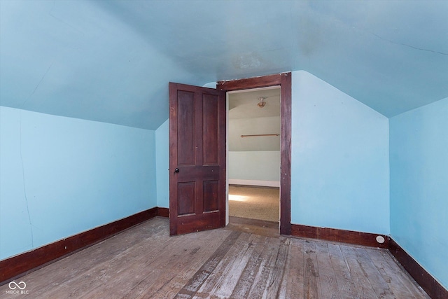 additional living space with hardwood / wood-style flooring and lofted ceiling