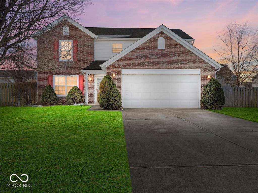 front facade featuring a garage and a lawn