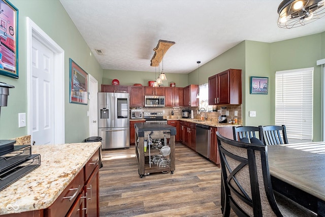 kitchen featuring a kitchen island, appliances with stainless steel finishes, dark hardwood / wood-style flooring, and decorative light fixtures