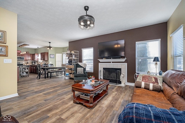 living room with a tiled fireplace, wood-type flooring, and plenty of natural light