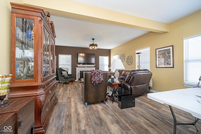 living room with beam ceiling, dark wood-type flooring, and a tile fireplace