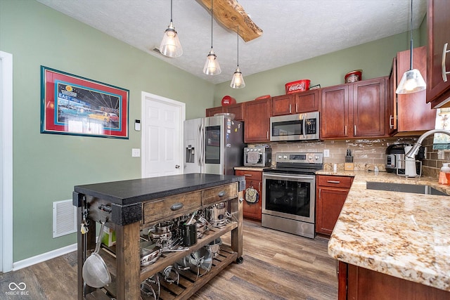 kitchen with appliances with stainless steel finishes, sink, backsplash, dark hardwood / wood-style flooring, and hanging light fixtures