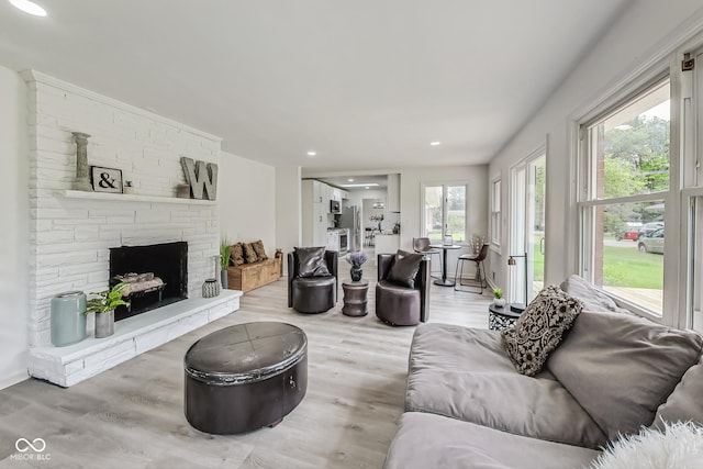 living room with a stone fireplace and light hardwood / wood-style flooring