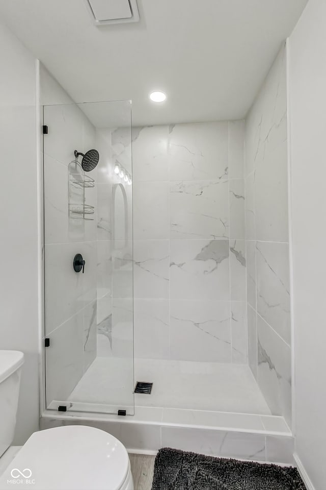 bathroom with a tile shower and toilet