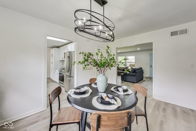 dining room with light hardwood / wood-style flooring and a notable chandelier