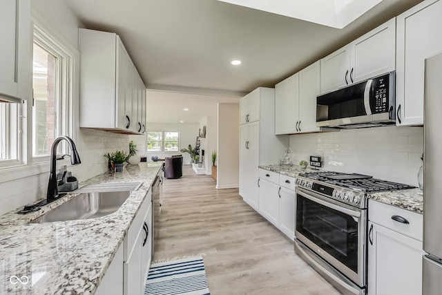 kitchen featuring light stone countertops, white cabinetry, appliances with stainless steel finishes, and sink