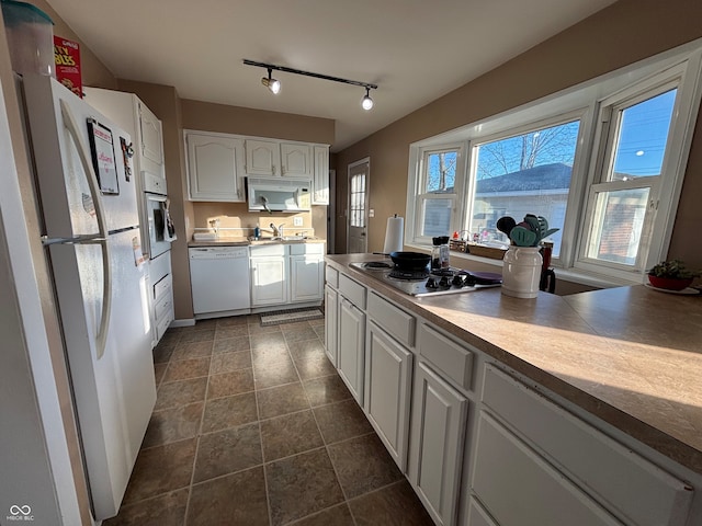 kitchen with white cabinetry, white appliances, dark tile patterned flooring, and sink