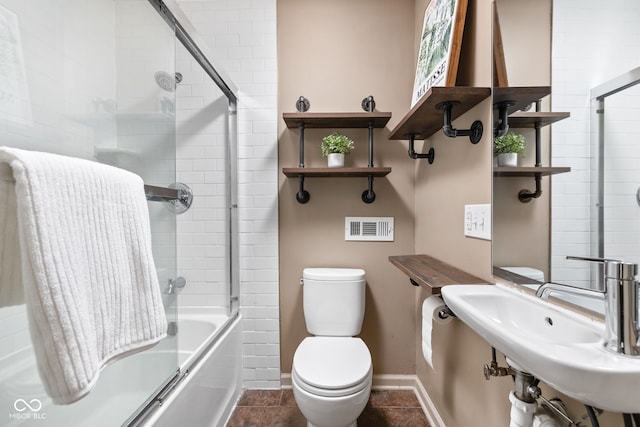 full bathroom with enclosed tub / shower combo, toilet, and sink