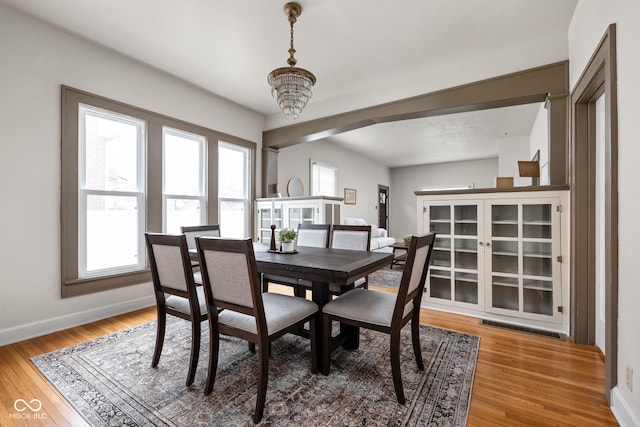 dining area with a notable chandelier, a wealth of natural light, and wood-type flooring