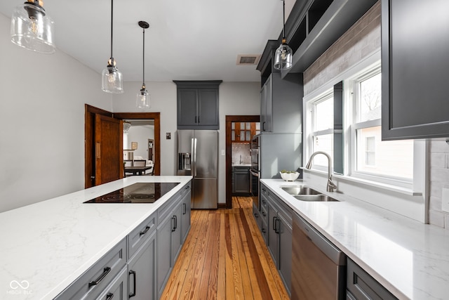 kitchen featuring pendant lighting, sink, light hardwood / wood-style flooring, appliances with stainless steel finishes, and gray cabinetry