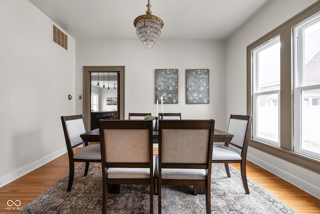 dining area with wood-type flooring and a chandelier