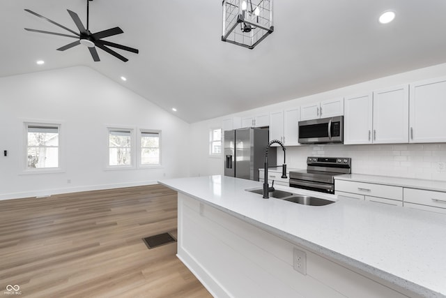 kitchen featuring appliances with stainless steel finishes, sink, white cabinets, light hardwood / wood-style floors, and light stone countertops