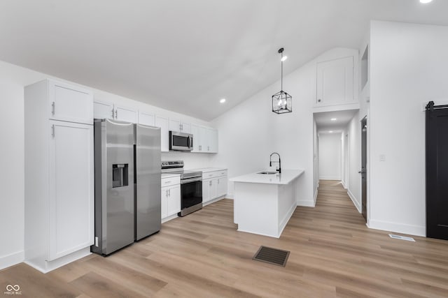 kitchen with hanging light fixtures, white cabinetry, appliances with stainless steel finishes, and light hardwood / wood-style flooring