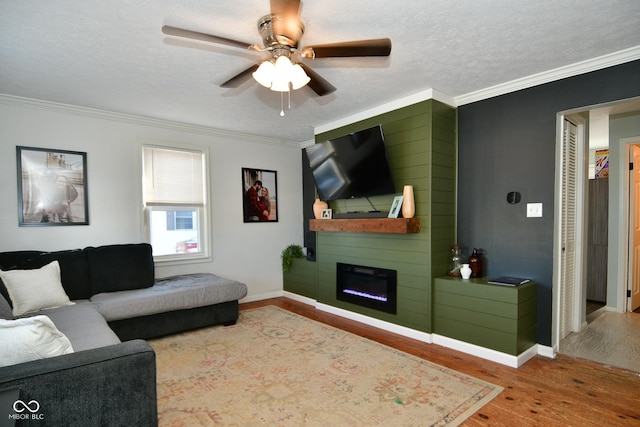 living room with hardwood / wood-style flooring, crown molding, a large fireplace, and a textured ceiling