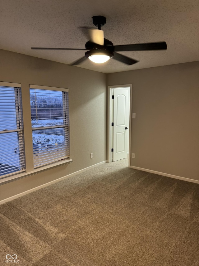 empty room with ceiling fan, a textured ceiling, and carpet