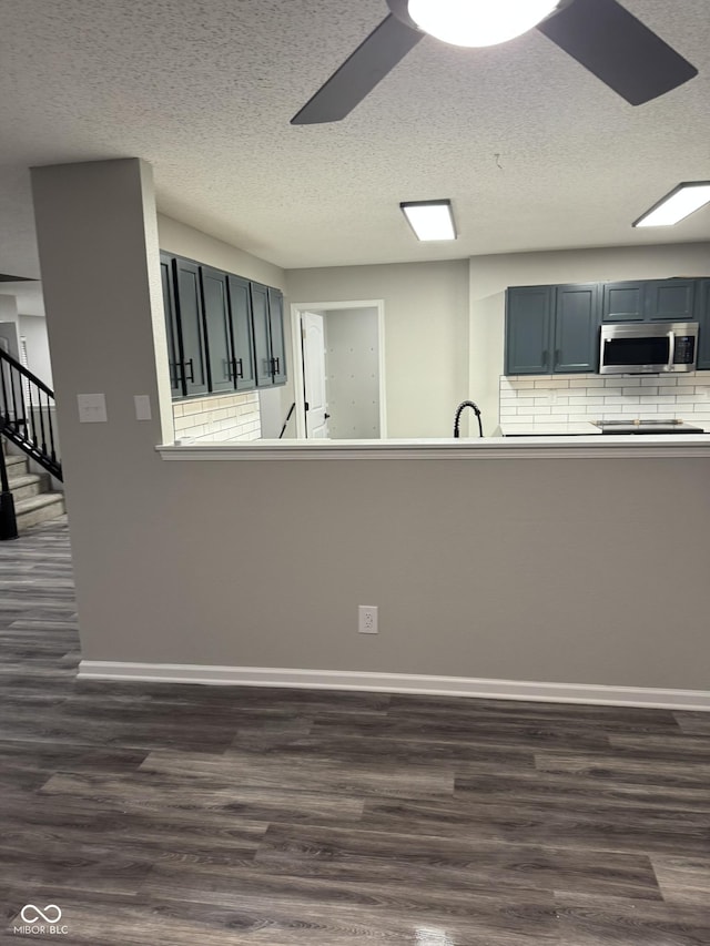 kitchen featuring dark hardwood / wood-style floors, backsplash, ceiling fan, and kitchen peninsula