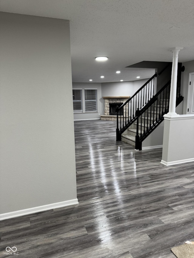 interior space with dark hardwood / wood-style flooring, decorative columns, and a textured ceiling