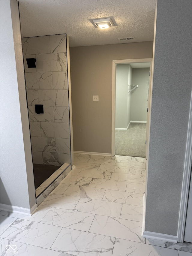 bathroom featuring tiled shower and a textured ceiling