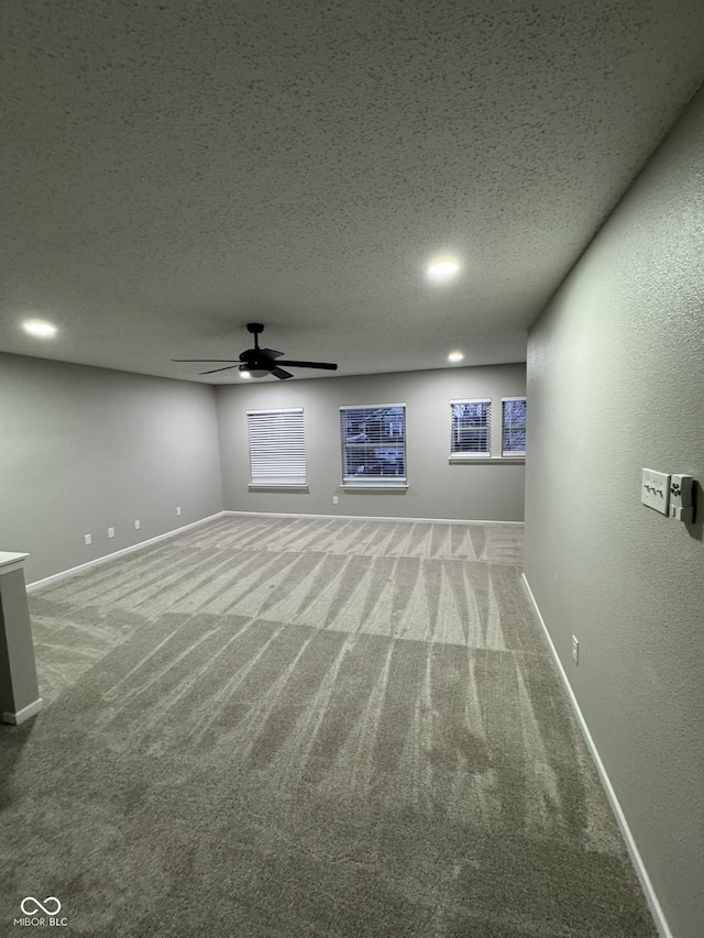 basement featuring ceiling fan, carpet flooring, and a textured ceiling