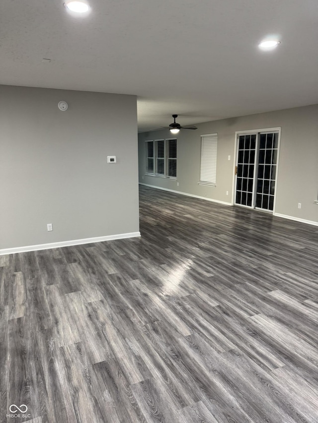 unfurnished living room with dark hardwood / wood-style flooring and ceiling fan