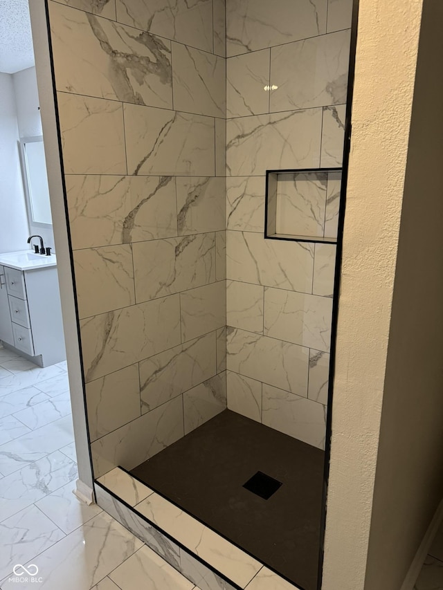 bathroom with tiled shower and vanity