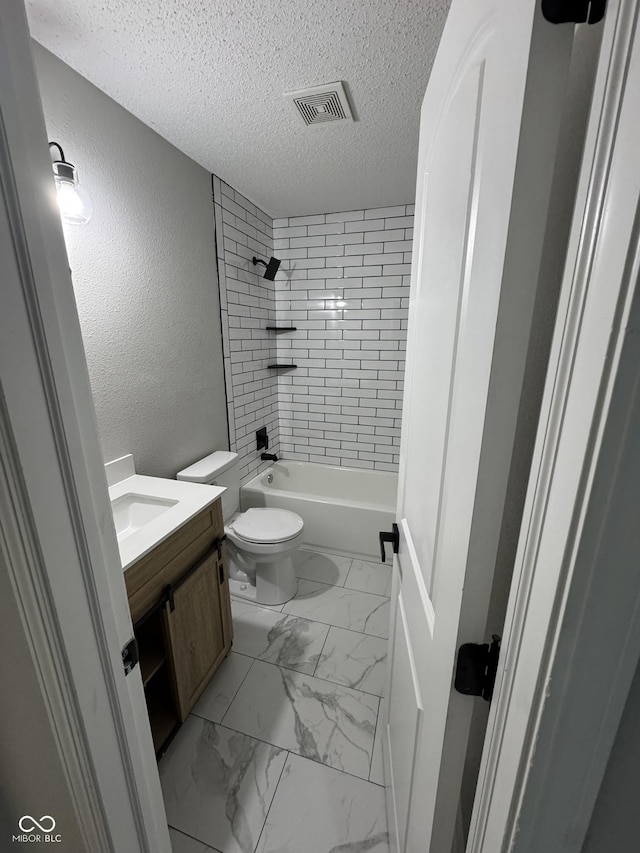 full bathroom featuring tiled shower / bath combo, vanity, a textured ceiling, and toilet