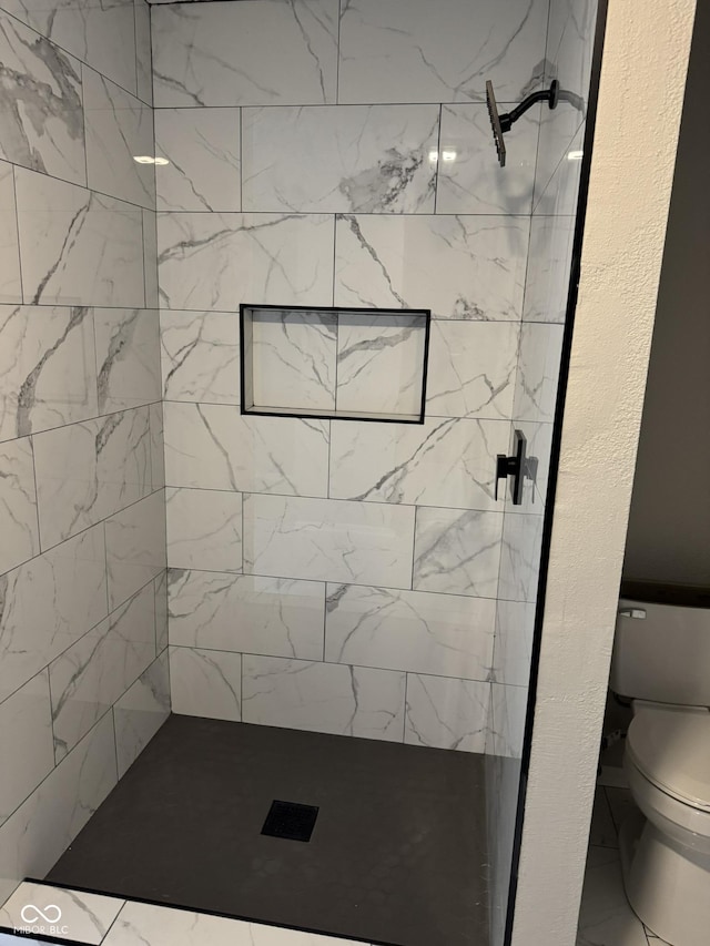 bathroom featuring tiled shower and toilet