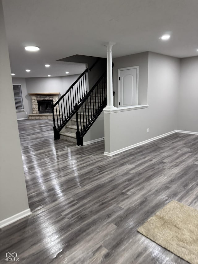 basement featuring a stone fireplace and dark hardwood / wood-style floors