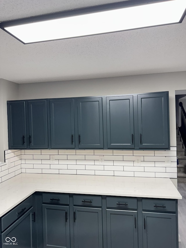 kitchen featuring blue cabinets, decorative backsplash, and a textured ceiling