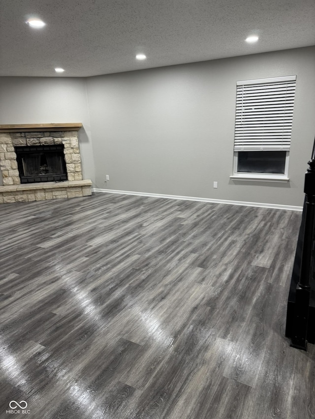 unfurnished living room featuring dark wood-type flooring, a fireplace, and a textured ceiling