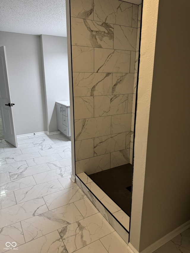 bathroom with a textured ceiling and tiled shower