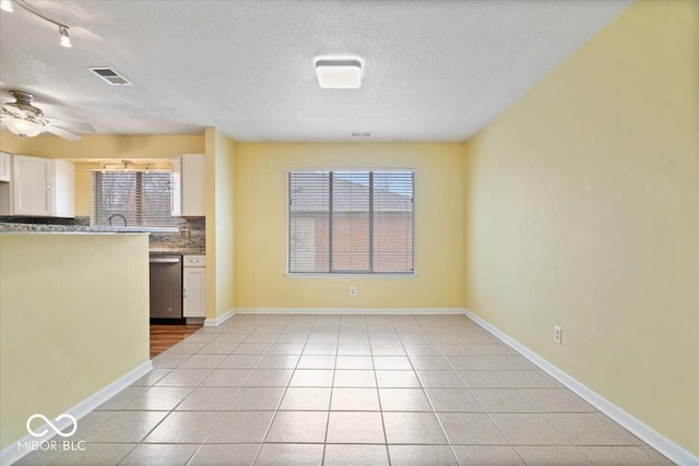 interior space featuring light tile patterned floors, dishwasher, ceiling fan, backsplash, and white cabinets