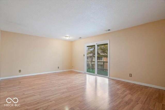 unfurnished room with a textured ceiling and light wood-type flooring