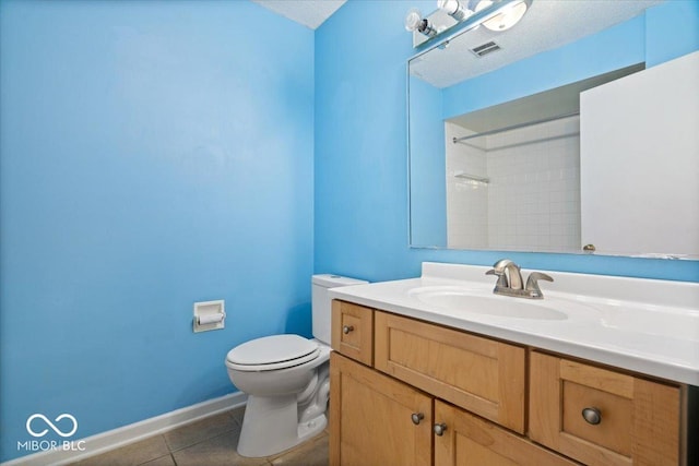 bathroom with tile patterned flooring, vanity, tiled shower, toilet, and a textured ceiling