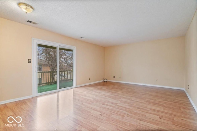 spare room featuring a textured ceiling and light wood-type flooring