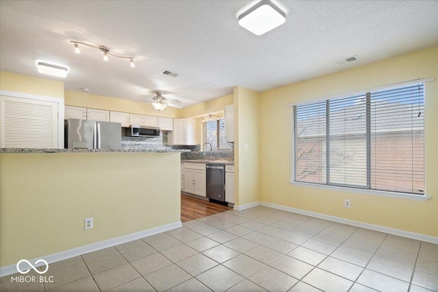 kitchen featuring light tile patterned floors, appliances with stainless steel finishes, white cabinetry, backsplash, and kitchen peninsula